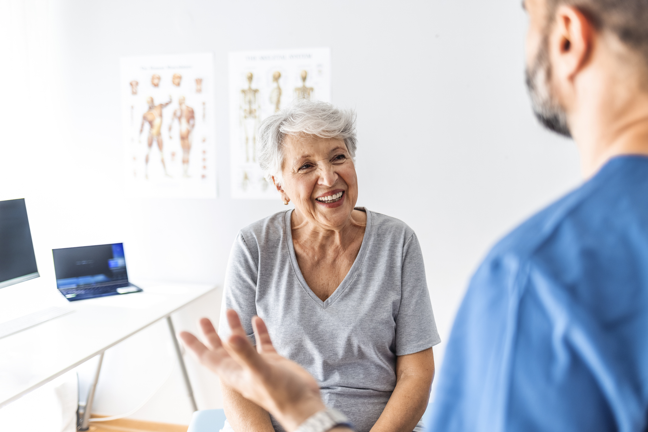 Senior woman talking with male nurse or doctor, receiving good news.